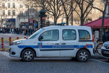 Paris. 02.02.2025 Bir belediye polis arabası canlı yayalar ve büyüleyici kafelerle çevrili canlı bir Paris caddesinde konuşlanmış ve şehrin enerjisinin özünü yakalıyor..