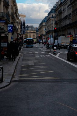 Paris, Fransa-2024-11-20 Şehir çevresi otobüsler, arabalar ve insanlar bulutlu bir gökyüzü altında hareketli bir cadde boyunca günlük şehir yaşamını vurguluyorlar..