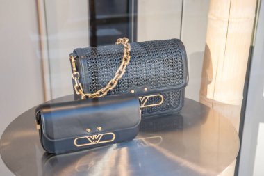 Paris. 02.02.2025. Açık bir öğleden sonra bir butik penceresinden süzülen güneş ışığıyla vurgulanan cilalı bir sergi masasının üzerinde duran iki zarif el çantası..