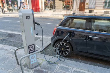 Paris. Fransa-02.02.2025. Sakin bir şehir caddesindeki modern bir istasyonda elektrik yüklü bir araç günlük hayatta sürdürülebilir taşımacılığa geçişi gösteriyor..