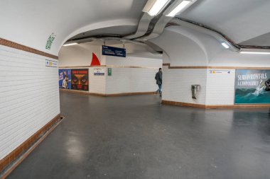 Paris. 02.02.2025. Yalnız bir yolcu, şehrin altındaki kentsel yaşam ve yaratıcılığın karışımını gösteren canlı posterlerle süslenmiş geniş bir metro koridorunda yürüyor..