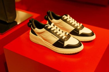 Paris, Fransa-2024-11-20 Siyah ve Beyaz spor ayakkabıları parlak kırmızı bir ekrana yerleştiriliyor. Parlak tasarımları ve zanaatkarlıkları, moda ayakkabılar üzerine odaklanan bir perakende satış ortamında ön plana çıkıyor..