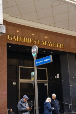 Paris, Fransa-2024-11-20 Paris 'teki Lafayette Galerisi' nin oradaki otobüs durağında bir grup insan bulutlu gökyüzü ve şehir telaşlı tipik bir gün sergiliyor..