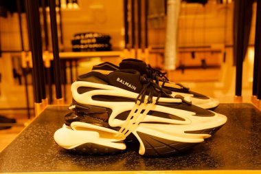 Paris, Fransa-2024-11-20 Bir çift modern siyah-beyaz spor ayakkabı, tasarımlarını geliştiren sıcak ışıklandırmayla aydınlatılmış, modaya uygun bir butikte belirgin bir şekilde sergilenir..