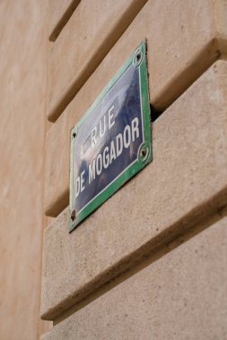 Paris, Fransa-2024-11-20 Bej taştan bir duvara monte edilmiş Rue de Mogador tabelasının yakın çekim görüntüsü aydınlık gün ışığında mimari detaylar sergiliyor..