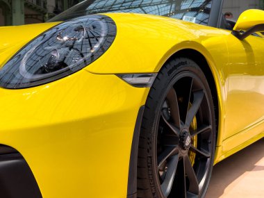 Paris, Fransa-04.02.2025 Renkli dış görünüşlü çarpıcı sarı spor araba bir otomotiv fuarında gururla duruyor, katılımcıların ve meraklıların dikkatini çekiyor..