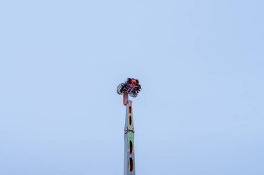 A group of excited riders experience a thrilling amusement ride high above the ground, enjoying breathtaking views as they reach the peak, capturing the joy of summer fun. clipart