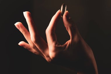 Bir el zarif bir şekilde Omega 3 içeren altın bir kapsül tutar. Arka plan karanlık, kalp ve beyin sağlığı için bu ilave maddenin önemini vurguluyor..