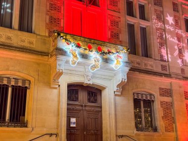 A charming building showcases holiday decorations with bright lights and ornaments, creating a festive atmosphere in the city at night during the Christmas season. clipart