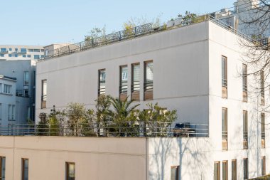 Paris, Fransa-14.01.2025 çatı bahçesi olan çağdaş bir bina şehir ortamında sergilenmektedir. Yapı birden fazla pencere ve yeşillik sergiliyor, estetik çekiciliğini artırıyor.