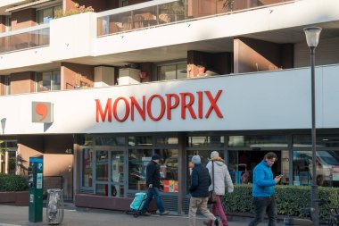 Paris, Fransa-14.01.2025 İnsanlar güneşli bir günde parlak kırmızı bir işaretle bir marketin önünden yürüyüp günlük sohbetlere ve alışveriş faaliyetlerine girişiyor..