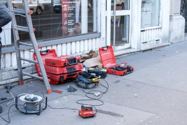 Paris 'in işlek bir caddesinde bir şantiye faaliyet ile dolup taşıyor. Çeşitli inşaat aletleri ve ekipmanlar kaldırımda düzgünce düzenleniyor. Parlak kırmızı araç valizleri ve güç cihazları dağınık yatıyordu