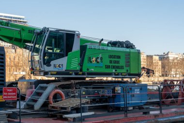 Fransa 'nın başkenti Paris' teki Seine Nehri yakınlarındaki bir şantiyeye büyük bir vinç yerleştirildi. Canlı yeşil ve beyaz bir tasarımı bulunan vinç raylara monte edilmiş, inşaat faaliyetlerine hazır.