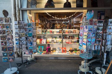 Paris, Fransa-13.01.2025 Büyüleyici bir kitapçının vitrininde gezginler canlı kitap ve kartpostallar sergiliyorlar. Pencerelerde renkli kitap kapakları, resim baskıları ve...