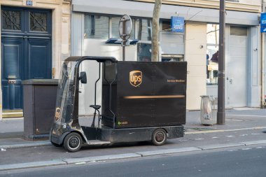 Paris, Fransa-14.01.2025 Bir kompakt teslimat aracı şehir caddesi boyunca park edilmiştir, dükkanlarla çevrilidir. Güneş parlıyor, açık bir günü ve kentsel çevreyi gösteriyor..