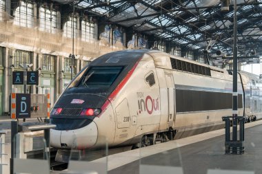 Paris, Fransa-14.01.2025. Yüksek hızlı bir tren büyük bir istasyondaki işlek bir tren peronunda duruyor. Parlak tasarımını sergiliyor. Gezginler, güneş sahneye sıcak bir ışık saçarken koşuşturuyorlar..