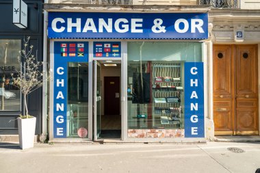 Paris, Fransa-14.01.2025 Bir döviz mağazası büyük bir mavi tabela ve cam mağaza vitrinine sahip, gündüz boyunca çeşitli bayraklar ve finans hizmetleri sergilenmektedir.