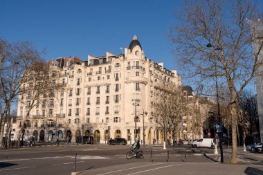 Paris, Fransa-13.01.2025 Paris 'te sakin bir caddede klasik Fransız mimari özelliklerini sergileyen zarif binalarla çevrili bir bisikletçi geziyor. Sahne güneşli bir kış gününü çıplak bir şekilde yakalıyor.