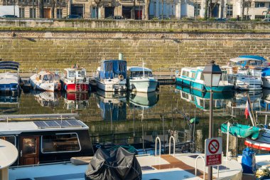 Paris, Fransa-14.01.2025 birkaç tekne sakin bir marinaya demirlemiştir. Yansımaları parlak, berrak bir gökyüzünün altındaki sakin suda görülebilir. Şehir yakınlarında huzurlu bir gün..