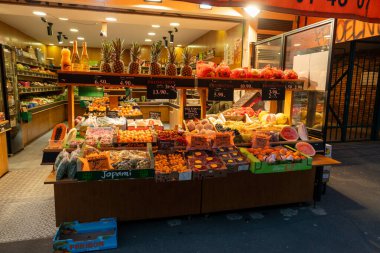 Paris 'teki hareketli bir pazarda renkli bir meyve standı, canlı taze ürünleriyle yoldan geçenleri cezbediyor. Ananas, karpuz ve portakallar çeşitli çeşitlerin yanında düzgünce dizilmiştir.