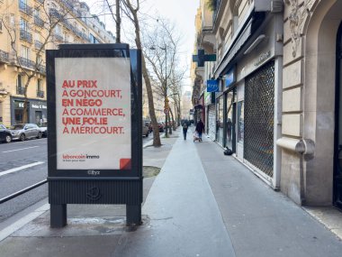 Paris, Fransa-16.02.2025 Yoğun bir caddede, yayalar yürürken gayrimenkul ilanları sergilenen, canlı bir atmosferde şehir yaşamını ön plana çıkaran büyük bir reklam ekranı..