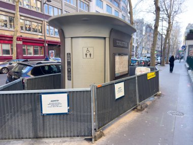 Paris, Fransa-16.02.2025 modern bir umumi tuvalet yapısı Paris 'in işlek bir caddesinde duruyor, yayalar için uygun erişimi sağlarken kentsel kentsel manzaraya entegre oluyor..