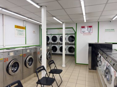 Paris, Fransa-20.02.2025 Parlak ve davetkar, çamaşırhane parlak makineler sunuyor ve ortak bir ortamda çamaşır yıkamayı bekleyen müşteriler için rahat bir yer..