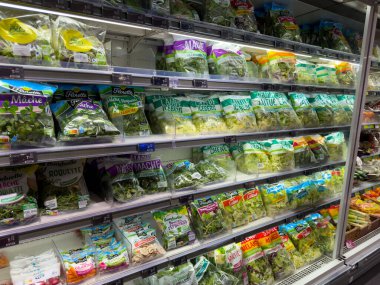 Paris,France-20.02.2025 A colorful array of packaged salad greens fills the shelves in a grocery store, showcasing the freshness and variety available for healthy meal choices. clipart