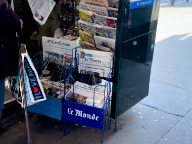 Paris, Fransa-23.02.2025 Canlı bir gazete bayii çeşitli gazeteler sergiliyor. Yoldan geçenleri güncel olaylara yetişmeye davet ediyor ve sabah atmosferinin tadını çıkarıyor..