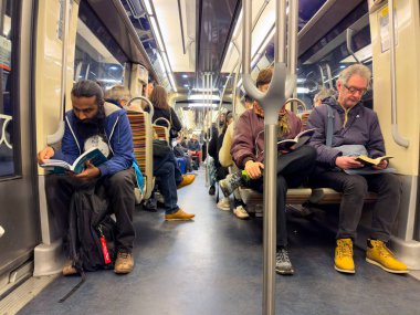 Paris, Fransa-23.02.2025 yolcuları, yoğun bir metro saatinde sakin bir atmosfer yaratarak kitaplarıyla sessizce meşgul olurlar. Tarzların ve odakların karışımı büyüleyici..