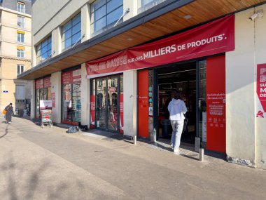 Paris, Fransa-23.02.2025 Alışverişçiler hareketli bir muhitte yoğun bir indirim mağazası keşfederken, parlak kırmızı pankartlar çok sayıda üründe önemli fiyat indirimleri duyurdu..