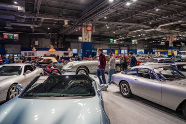 Paris, Fransa-09.02.2025 Heyecanlılar heyecan verici bir otomobil fuarında geziniyorlar, çarpıcı klasik arabalara hayran kalıyorlar ve hareketli bir salonda diğer tutkulu hayranlarla canlı sohbetler yapıyorlar..