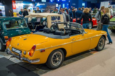 Paris,France-09.02.2025 A vibrant yellow convertible stands proudly amidst a crowd of classic car enthusiasts at a lively exhibition, surrounded by beautifully restored vehicles. clipart