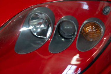 Paris, Fransa-09.02.2025 Kırmızı spor arabaların farları ve trafik lambaları incelendi. Garaj ışıkları altında çekici bir şekilde parladı. Mühendislik dehasının altını çizdi..
