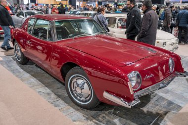 Paris, Fransa-09.02.2025 Çarpıcı kırmızı bir klasik araba, hayranları tarafından çevrelenmiş ve benzersiz tasarımı ve tarihi takdir edilen, hareketli bir otomobil fuarının ortasında dikkat çekiyor..