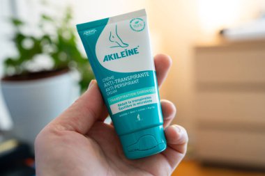 Paris, Fransa-09.02.2025 Kişi terlemeyle mücadele etmek için bir tüp krem taşır, egzersiz sırasında veya yoğun aktiviteler sırasında kuru ayakları temin eder, konforu korumak için idealdir..