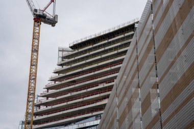 Paris, Fransa-09.02.2025 İşçiler, kentsel bir manzarada inşaat vinci ve komşu binalar tarafından çerçevelenen çağdaş bir yapı üzerindeki çalışmalarına özenle devam ediyorlar..