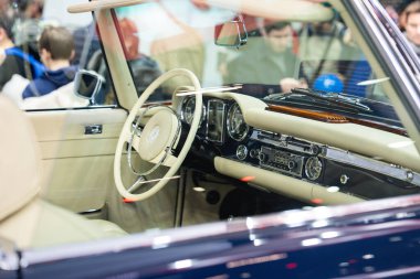 Paris, Fransa-09.02.2025 Vintage araba meraklıları, şehir merkezindeki yıllık bir otomotiv fuarında gösterilen klasik bir aracın özenle hazırlanmış iç mekanına hayran..