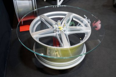 Paris, Fransa-09.02.2025 Bu eşsiz kahve masası stil ve fonksiyonları harmanlıyor, parlak bir otomotiv fuarında cam bir yüzey ile kaplı parlak bir araba tekerleği tabanı sergiliyor..