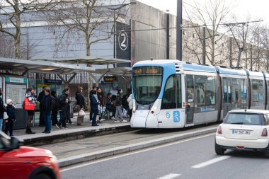 Paris, Fransa-09.02.2025 İnsanlar tramvay durağında toplanıyor, bazıları çantalarıyla, modern bir tramvay geldiğinde, şehir hayatının canlı ritmini gözler önüne seriyor..
