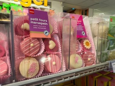 Paris, Fransa-25.02.2025 Çeşitli badem ezmesi şeffaf ambalajlama, canlı renkleri ve karmaşık tasarımları vurgulanıyor, müşterileri hoşgörülü olmaya davet ediyor.