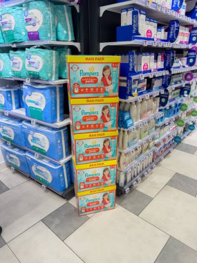 Paris, Fransa-25.02.2025 Dolu bir mağaza koridorunda, çeşitli bebek bakım ürünleriyle çevrili parlak renkli bebek bezi kutuları duruyor..