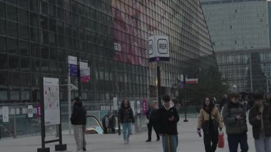 Puteaux, Fransa-14.2024 Canlandırılmış bir şehir meydanında hareketli bir faaliyet merkezi ortaya çıkar, burada insanlar yürür ve bağlanır, karanlık çöktüğünde çağdaş mimariye saldırarak çerçevelenir..