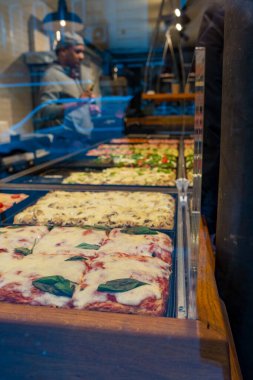 Paris, Fransa-23.11.2024 Renkli ve cezbedici pizza dilimleri zarif bir İtalyan restoranında düzenlenir. Müşterileri çeşitli ve taze malzemeleriyle davet ederler..