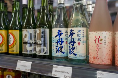Paris, Fransa-23.11.2024 çeşitli sake şişeleri canlı bir Japon pazarında renkli bir rafta dizilmiştir. Etiketler benzersiz tasarımlar ve karakterler, geleneksel zanaatkarlık sergiliyor.