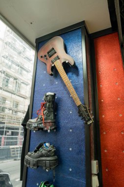 Paris,France-23.11.2024 Roller skates hang alongside a vibrant guitar against a colorful wall in a trendy urban shop, showcasing a fusion of music and skate culture. clipart