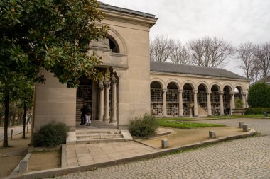 Paris, Fransa-23.11.2024 Ziyaretçiler Paris 'teki zarif bir mezarlıktan geçerek bulutlu gökyüzünün altındaki karmaşık taş mimariye hayran kaldılar..