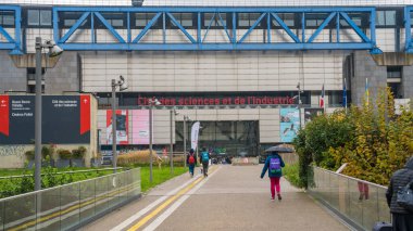 Paris, Fransa-03.12.2024 Ziyaretçiler, yağmurlu şehir ortamında hareketlilik vızıldarken, canlı bilim ve endüstri kompleksine doğru yürüyorlar..
