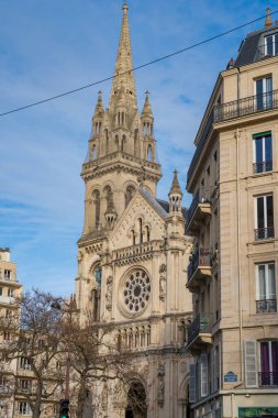 Paris, Fransa-20.20.2024 Karmaşık detayları olan güzel bir kilise güneşli bir günde aydınlık gökyüzü tarafından aydınlatılan klasik Paris binaları ve ağaçlarıyla çevrili..