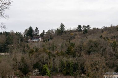 Tepe kenarındaki evler, La Roche-Guyon 'daki ağaçların iskelet dallarını dikizler. Bu güzel Fransız mahallesinde huzurlu bir kış ortamı ortaya çıkar..